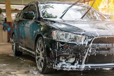 The black car wash with foam soap at home. Car detailing concept.の写真素材