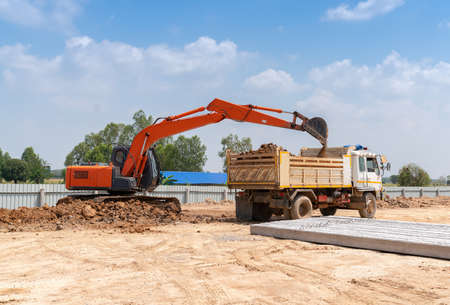 Excavator loading soil to dumper truck in construction site.