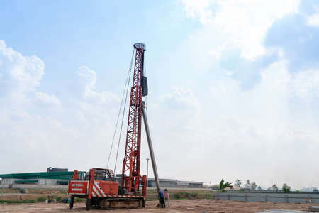 The pile driver is raising the piles and hammering them with the support of workers.