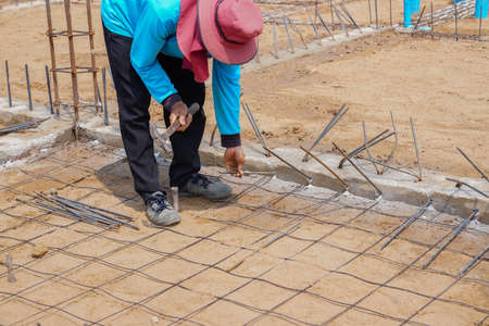 Industrial worker installing steel bar and binding wires before poor cement.の写真素材