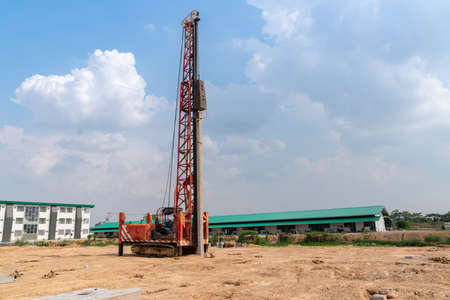 A pile driver is driving piles into the ground at a construction site.の写真素材