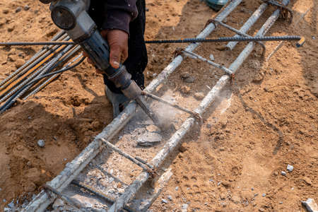 The workers use jackhammer to splitting the cement beams for bundle more steel bar.の写真素材