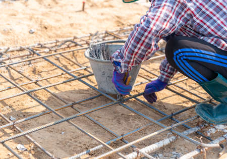 Worker bundle wire steel bar ground floor building in construction siteの写真素材
