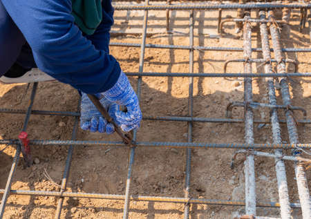 Worker using wire and pliers to tie the rebar 
 for building foundationsの写真素材