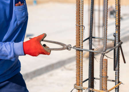 Workers tie wire to rebar to pour concrete poles in building construction site.の写真素材