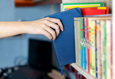 He has got the book he needs. Someone taking a book from the book shelf .の写真素材