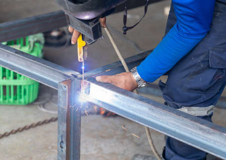 Worker welding leg of table with his hands, sparks without gloves. Don't safety