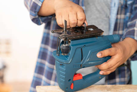 Close up male hands adjust angle base jigsaw with hexagon wrench to cut wooden.の写真素材