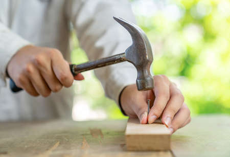 Close up hammering hit nail into wooden bar on out of focus background.の写真素材