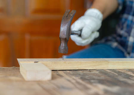 The man hit nail on wood bar selective focus and blur background.の写真素材