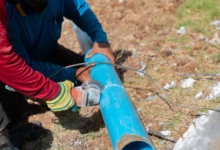 Two workers cutting pvc trough / spout for rooftop rainwater drain, Tap water systerm.の写真素材