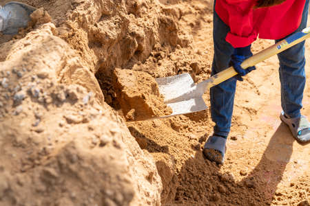 Close up worker pours sand with a shovel onto a trolley for transporting and mixing cement.の写真素材