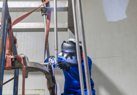 Industrial welder welding stainless steel truss structure assembly in factory, Welding process by Shielded Metal Arc Welding. Work at height.の写真素材