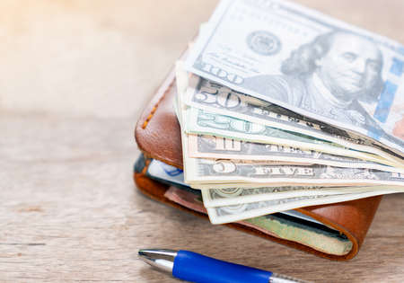 Leather wallet full of money on wooden table. Cash of dollar bills, Economic and financial concept.の写真素材