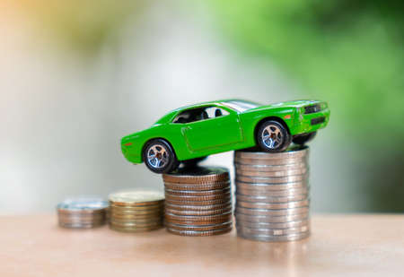 Car climb coin stack to hight on out of focus background. Concept of finance, leasing, saving and...