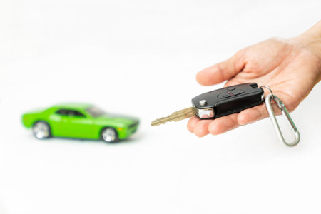 Car salesman gave the keys to the customers and out of focus model car on isolate white background.の写真素材