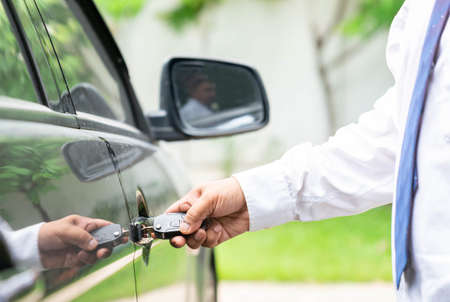 Business man open car door with car key on out of focus background. Business, finance and leasing...