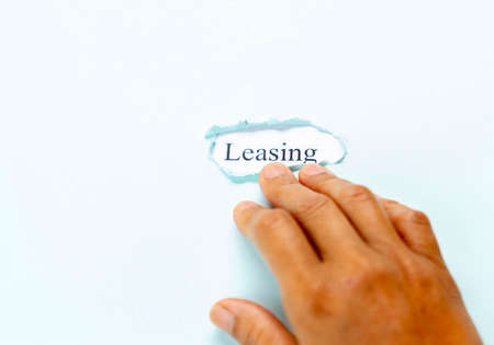 Hand point leasing on light blue paper, concept of finance and leasing. isolate ligh blue background.の写真素材