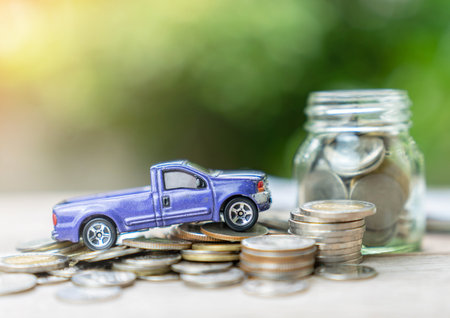 Blue miniature pickup model and golden coins pile on out of focus background. - Finance and car loan, saving money for a car concepts.の写真素材