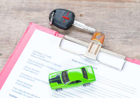 Green toy car and key, concept in insurance,loan,finance and buying car backgroundの写真素材