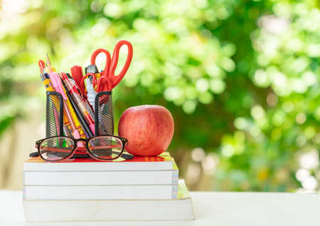 Book stack, glasess, stationery and apple paste on table in the garden.の写真素材