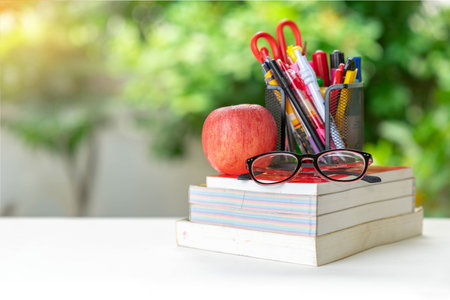 Glasses, apple and stationery pile on book stack in the garden. Concept of international literacy dayの写真素材