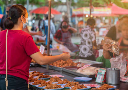 Woman buying food on street food market in the everning. Asis market.の写真素材