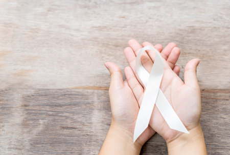 White ribbon on two hand in wooden background concept of international day of non-violence.の写真素材