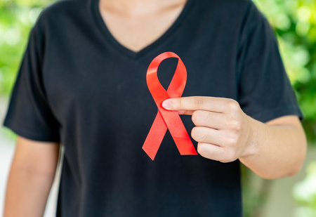 The man in black shirt show red ribbon in hand for the fight against AIDS. Concept of world aids day.の写真素材