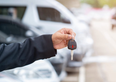 Business man's hand holding car key.Automobile rent or leasing concept