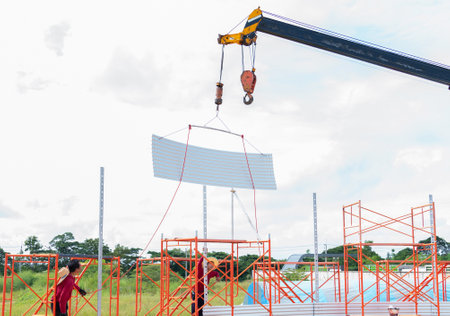 Crain lifting metal sheet silo wall in construction site. Work at height.の写真素材