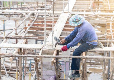 Worker hit nails on second floor for instruction formwork in building site.の写真素材