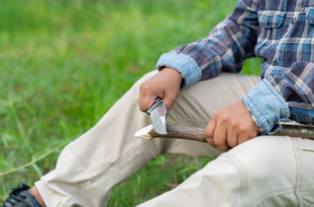 The man traveler Plane Knife With Wooden Stick, Hands Close-up. Concept of bushcraft survival and scouting.の写真素材
