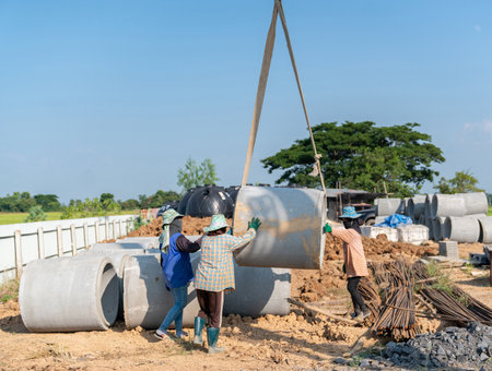 Workers are sorting large concrete pipes at a construction site. Mobile crain liftingの写真素材