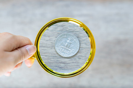 Silver dollar coin collection and round vintage magnify glass on wooden table.の写真素材