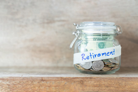 Coins and dollar bills in glass jar with retirement label for money saving financial conceptの写真素材
