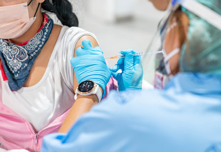Hand of medical staff in blue glove injecting coronavirus covid-19 vaccine in vaccine syringe to arm...