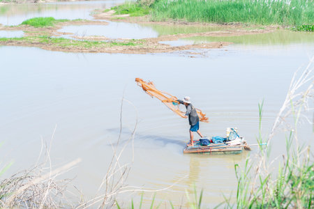 The old man fishing with a throwing net in the canal.の写真素材
