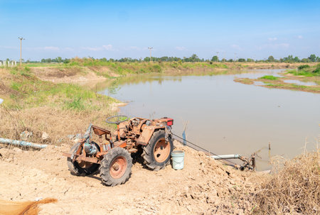 Tractor pumping water from a canal to the rice field. Countryside.の写真素材