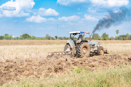 Tractor plows a field in the spring, with blue sky.の写真素材