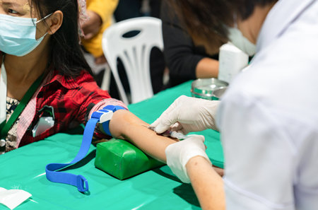 A nurse is using a needle to draw blood for an examination at the annual health checkup.