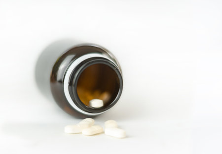 White medical pills and tablets spilling out of a drug bottle on isolate white background.の写真素材