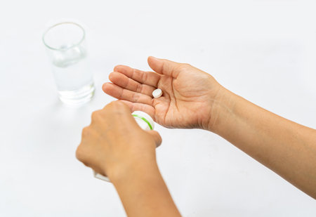 Woman holding a pill in her hand preparing to take it, on isolate white background.の写真素材