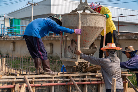 Workers during concrete pouring into formwork at construction site.の写真素材