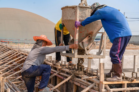 construction workers pour raw concrete using from bucket into the formwork at the construction site.の写真素材