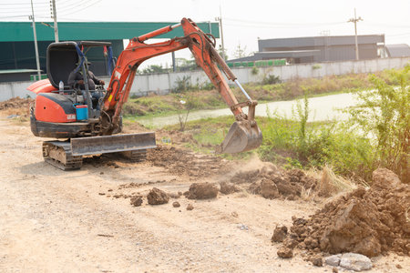 Mini excavator is adjusting the road at the edge of the pond in the factory.の写真素材