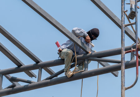 Welder working on a steel roof structure Male welder welding steel at construction siteの写真素材