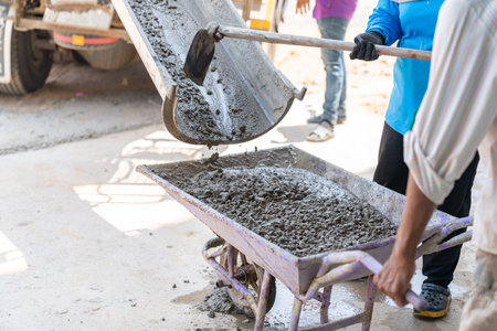 Workers load concrete from trucks to cart for pouring the floor inside. Construction site.の写真素材