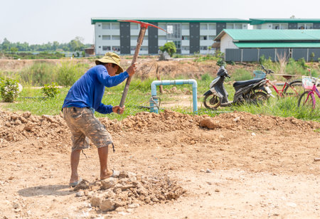 Workers use pickaxe digging the soil surface to level it before pouring concrete.の写真素材