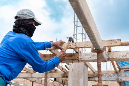 Worker Hit Nail on wooden stick for support scaffolding In building Site.